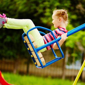 Happy little girl swinging on playground area